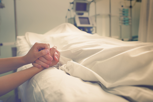 image of woman holding hand of someone who passed away in the hospital