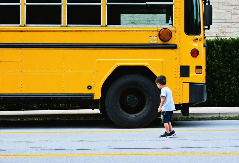 A kid walking toward a school bus to go to school.